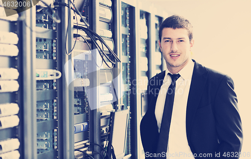 Image of businessman with laptop in network server room