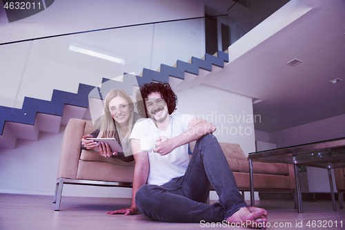 Image of couple relaxing at  home with tablet computers