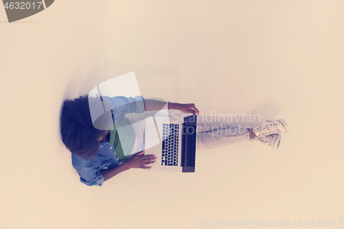 Image of african american woman sitting on floor with laptop top view