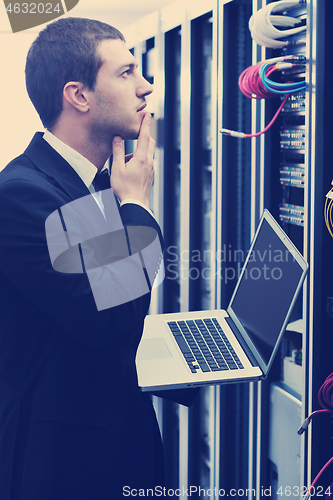 Image of businessman with laptop in network server room