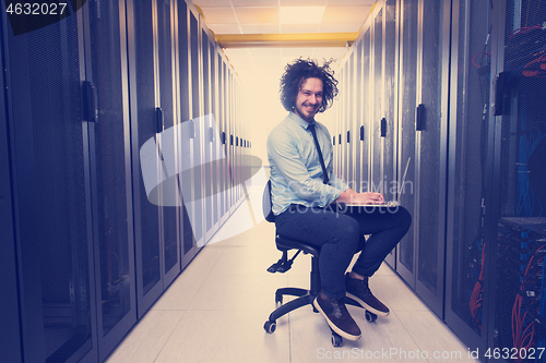 Image of engineer working on a laptop in server room