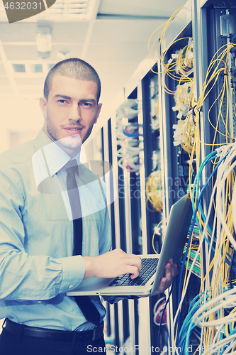 Image of businessman with laptop in network server room