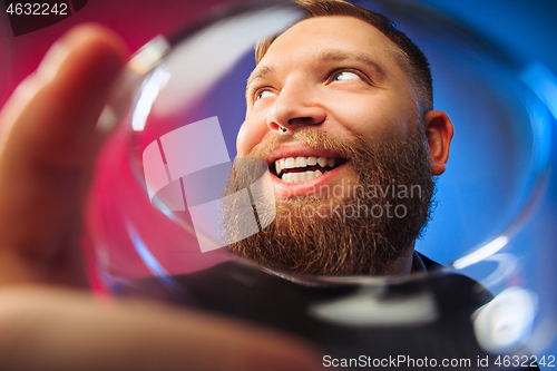 Image of The surprised young man posing with glass of wine.