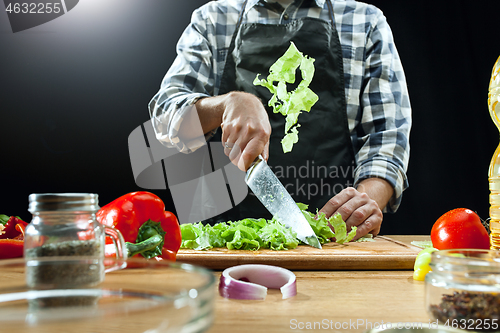 Image of Preparing salad. Female chef cutting fresh vegetables. Cooking process. Selective focus