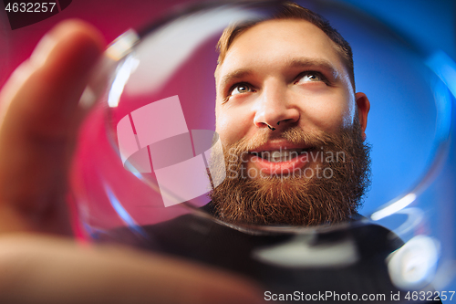 Image of The surprised young man posing with glass of wine.