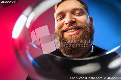 Image of The surprised young man posing with glass of wine.