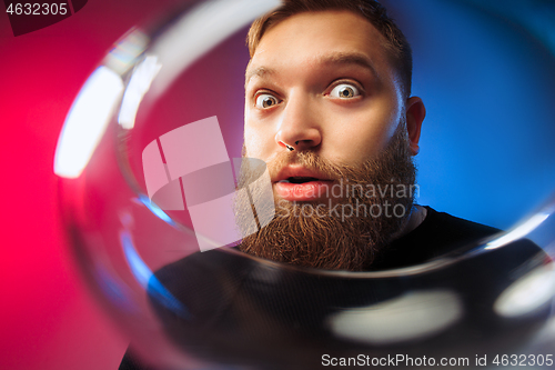 Image of The surprised young man posing with glass of wine.