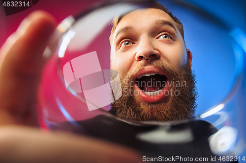 Image of The surprised young man posing with glass of wine.