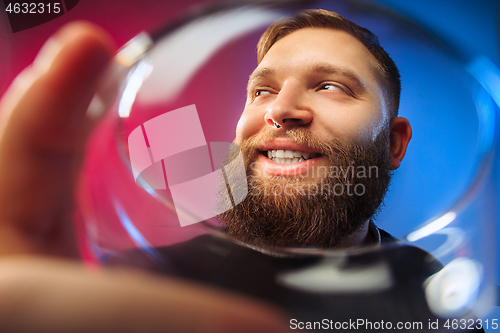 Image of The surprised young man posing with glass of wine.