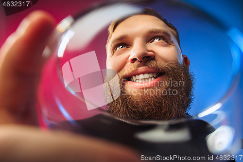 Image of The surprised young man posing with glass of wine.