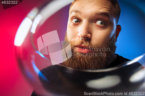 Image of The surprised young man posing with glass of wine.