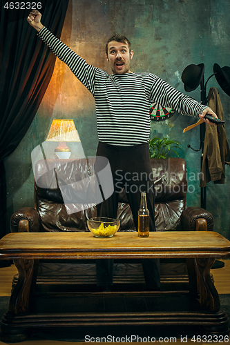 Image of Winner. Overwhelmed cheerful man moving hands while celebrating the victory of a favourite football team