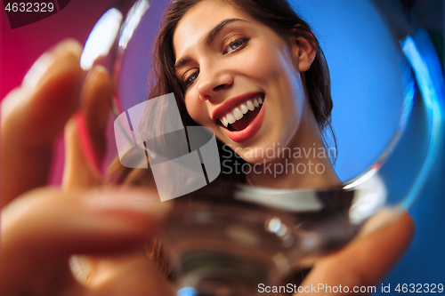 Image of The surprised young woman in party clothes posing with glass of wine.