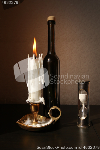 Image of Sandglass, candlestick and black bottle 