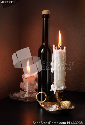 Image of Two candlesticks and black bottle