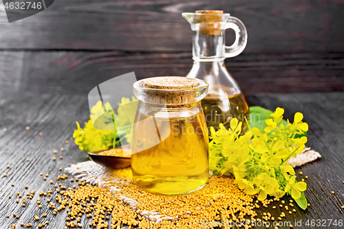 Image of Oil mustard in jar and decanter with flower on wooden board