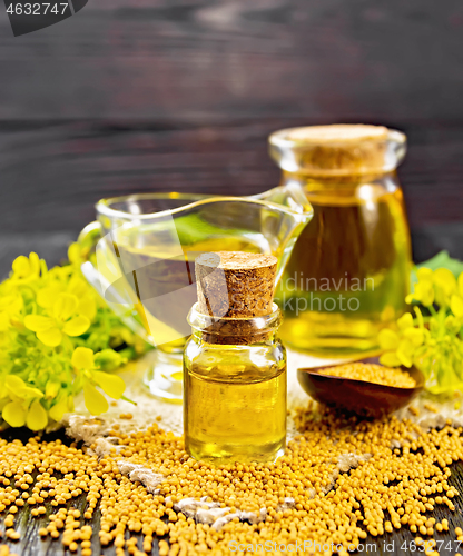 Image of Oil mustard in two jars and gravy boat on dark board