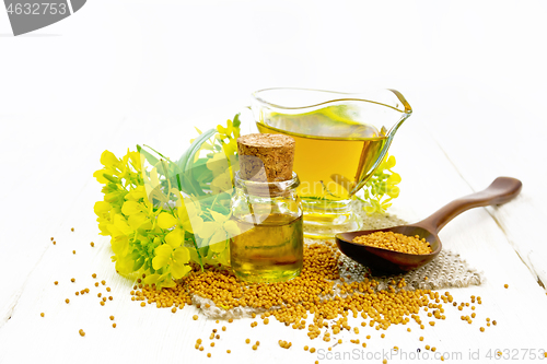 Image of Oil mustard in jars and gravy boat on light wooden board
