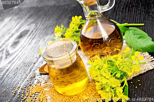 Image of Oil mustard in jar and decanter with flower on black board
