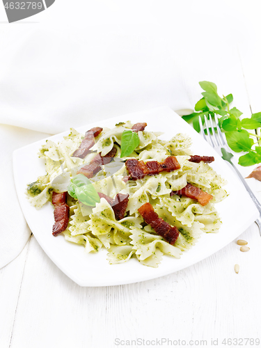 Image of Farfalle with pesto and bacon in plate on table