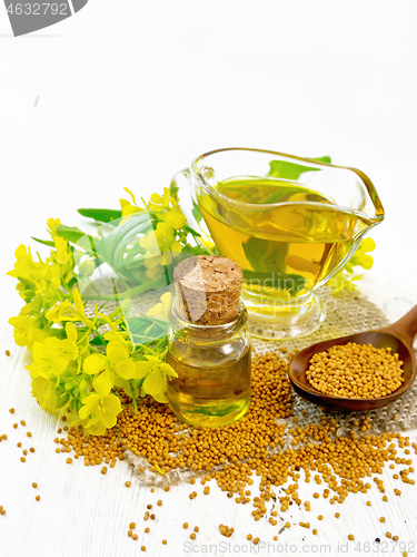 Image of Oil mustard in jars and gravy boat on wooden board