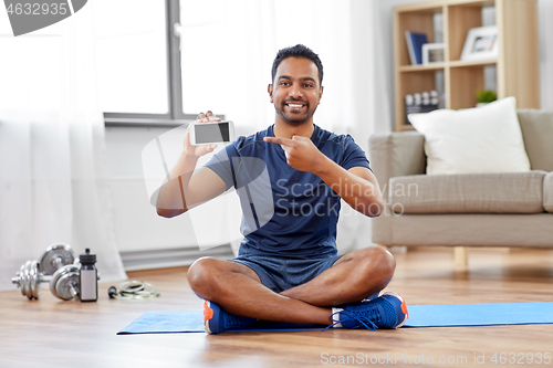 Image of indian man with smartphone on exercise mat at home