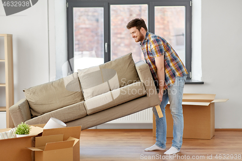 Image of happy man moving sofa at new home