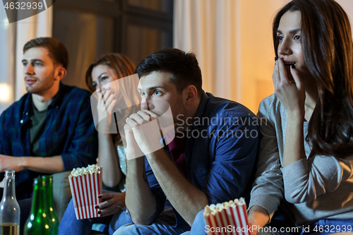 Image of friends with beer and popcorn watching tv at home