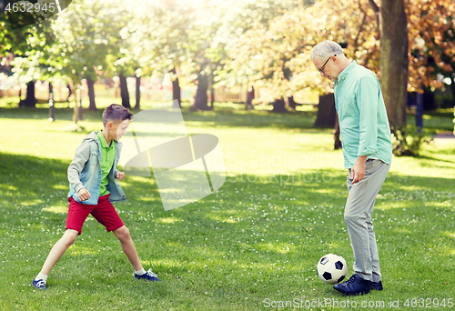 Image of old man and boy playing football at summer park