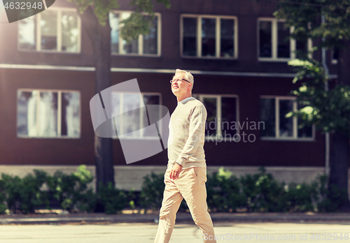 Image of senior man walking along summer city street