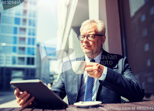 Image of senior businessman with tablet pc drinking coffee