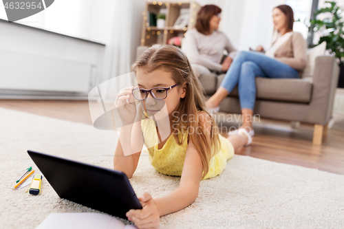 Image of girl with tablet computer lying on floor at home