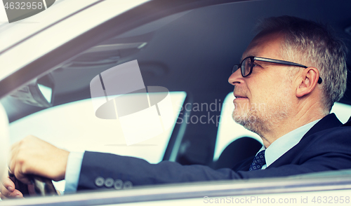 Image of happy senior businessman driving car