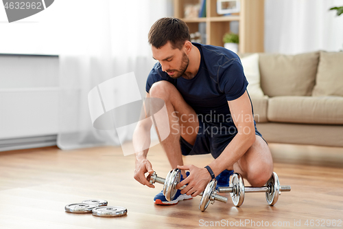 Image of man assembling dumbbells at home