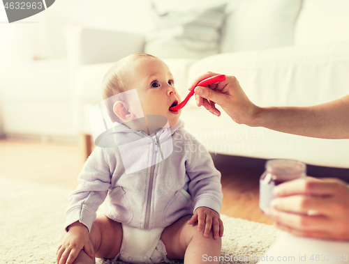 Image of mother with spoon feeding little baby at home