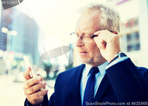 Image of senior businessman with smartphone in city