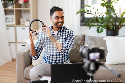 Image of male blogger with headphones videoblogging at home