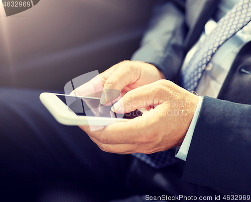 Image of senior businessman texting on smartphone in car