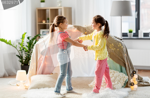 Image of happy girls playing near kids tent at home