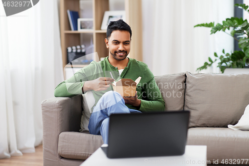 Image of indian man with laptop eating takeout food at home