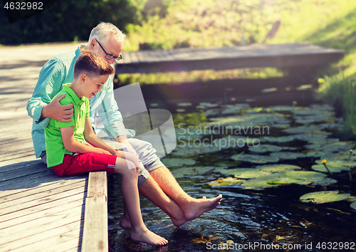 Image of grandfather and grandson sitting on river berth