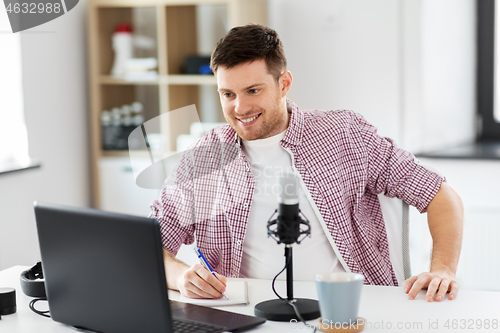 Image of audio blogger with laptop, microphone and notebook