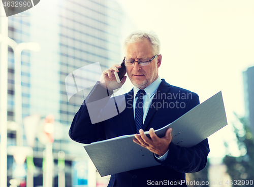 Image of senior businessman calling on smartphone in city