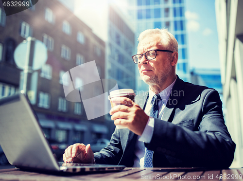 Image of senior businessman with laptop drinking coffee