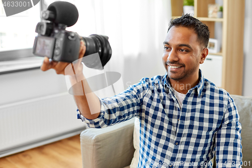 Image of male video blogger with camera blogging at home