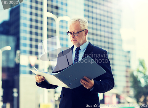 Image of senior businessman with ring binder folder in city