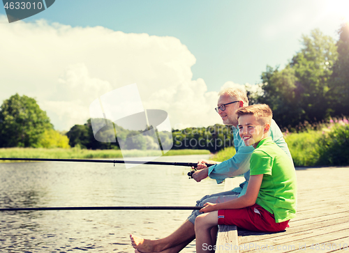 Image of grandfather and grandson fishing on river berth