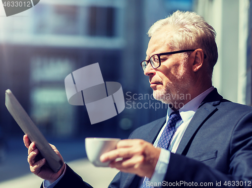 Image of senior businessman with tablet pc drinking coffee