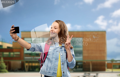 Image of girl taking selfie by smartphone over school