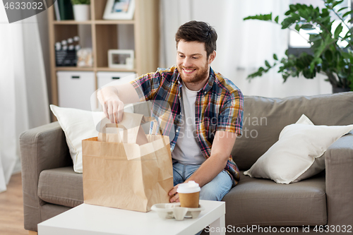 Image of smiling man unpacking takeaway food at home